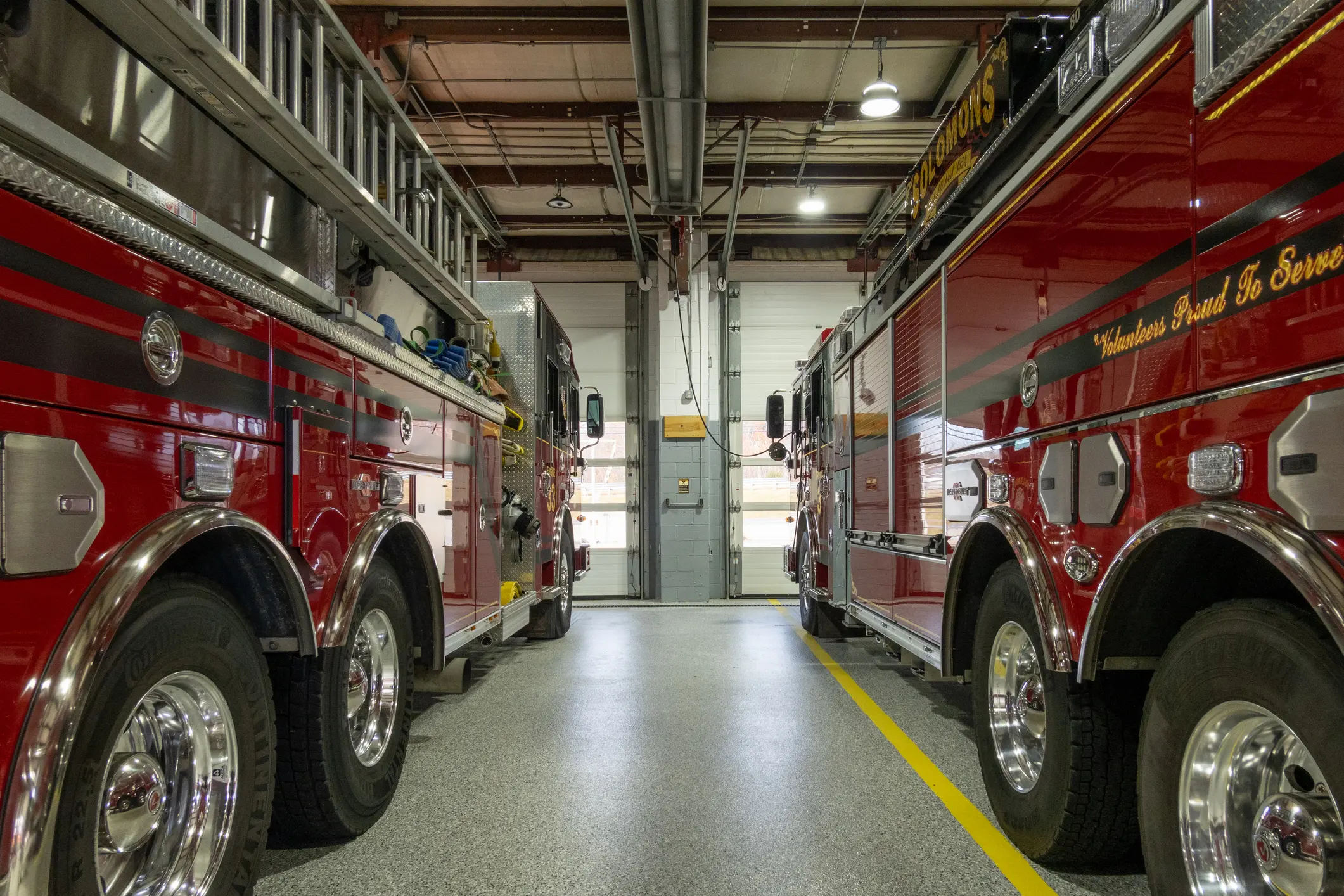 View from between two fire department apparatus in the bay of a fire station.