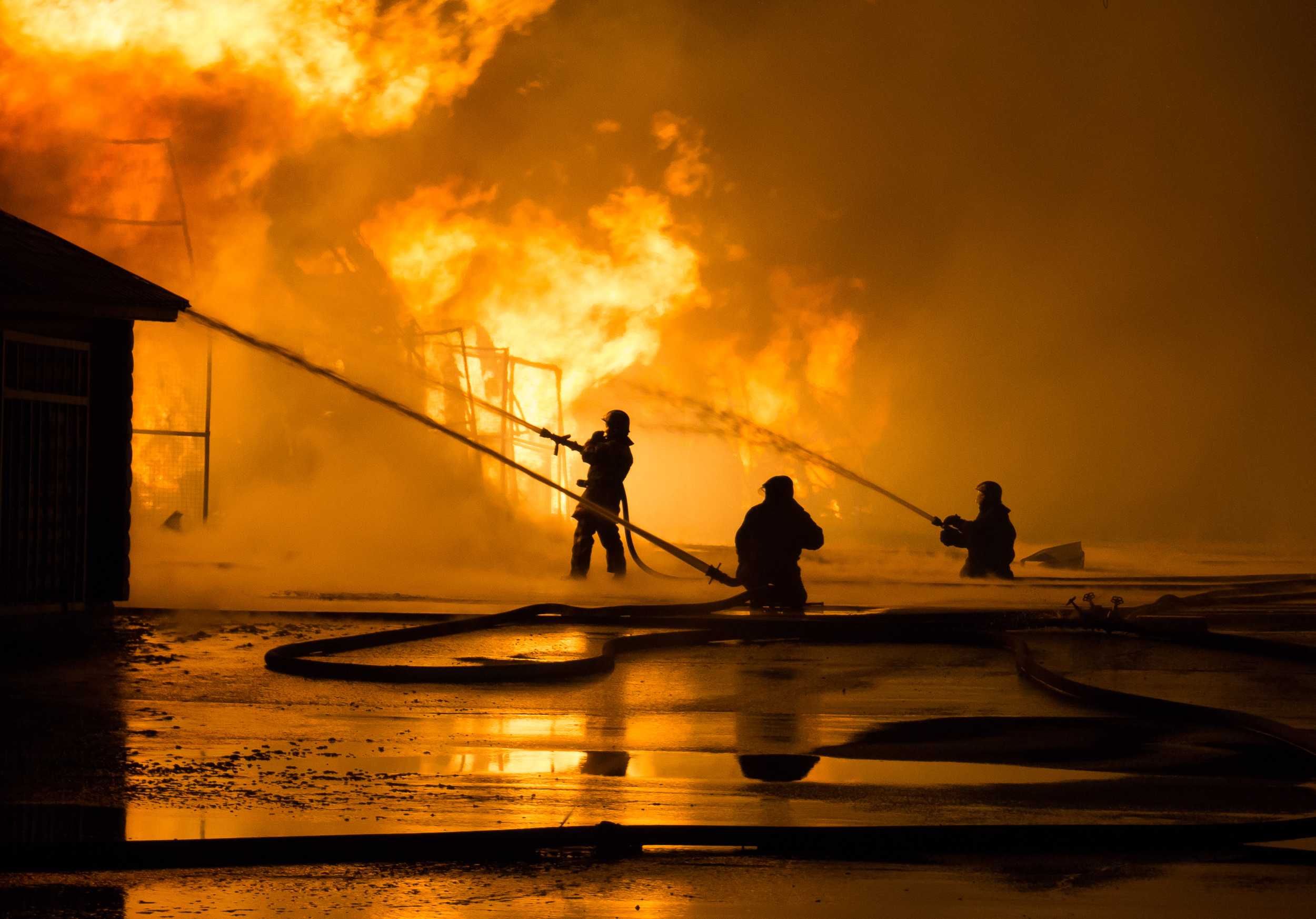 Two firefighters battling a car fire