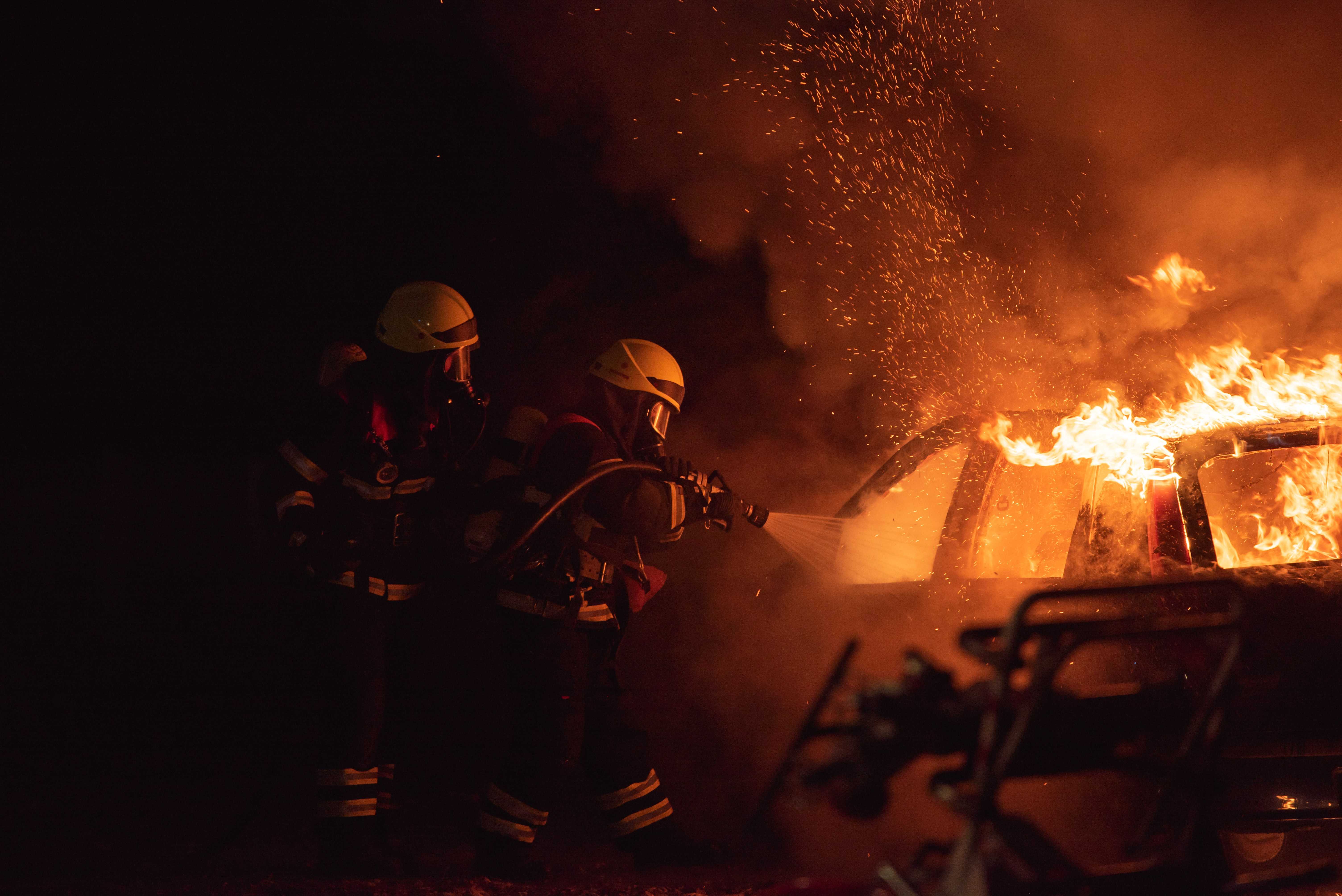 Two firefighters battling a car fire